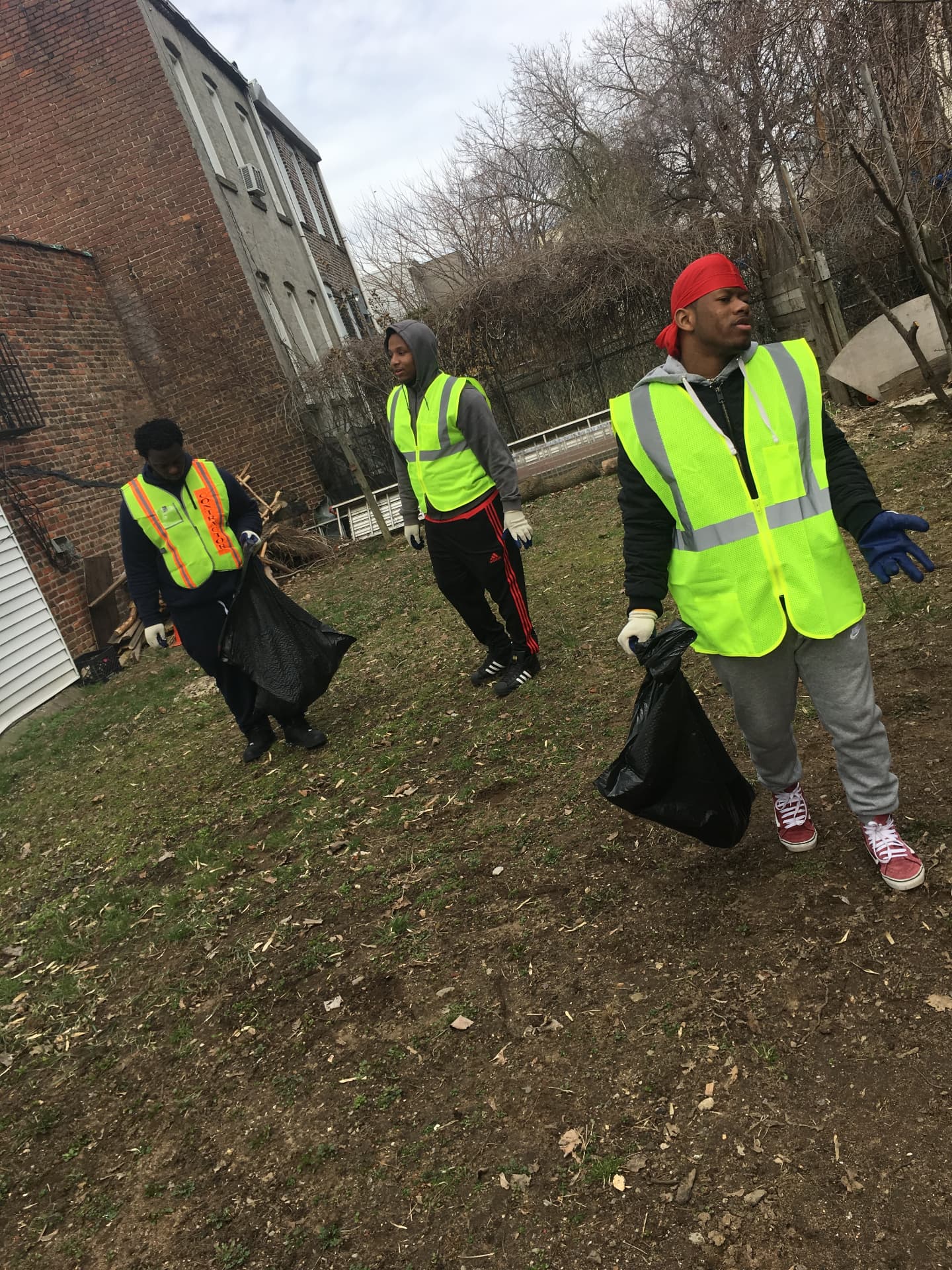 Youth in safety vests cleaning up a neighborhood lot